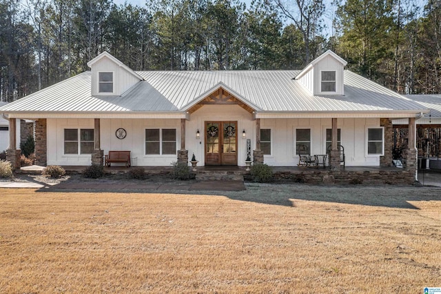 view of front of house with covered porch, a front lawn, and metal roof