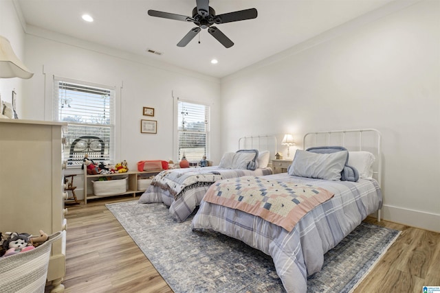 bedroom with light wood-style flooring, visible vents, and crown molding