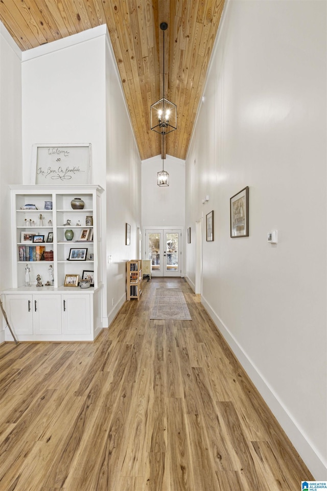 corridor featuring french doors, an inviting chandelier, light wood-type flooring, wooden ceiling, and baseboards