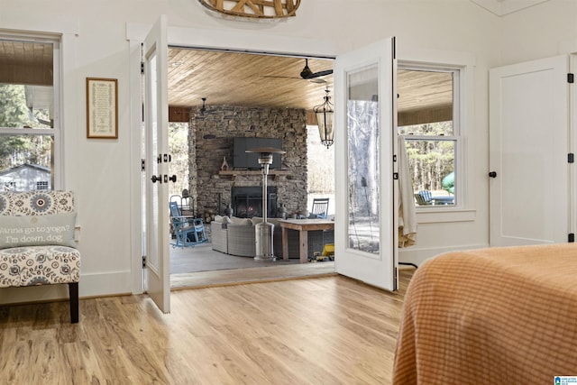 bedroom featuring access to exterior, wooden ceiling, a fireplace, and wood finished floors