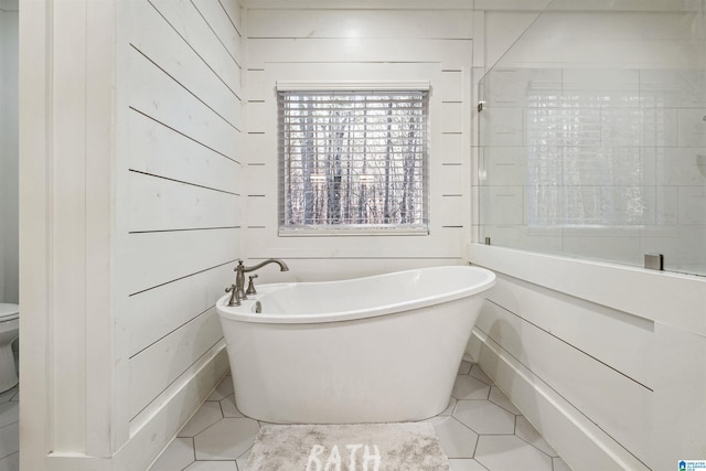full bathroom featuring toilet, a freestanding tub, and tile patterned flooring