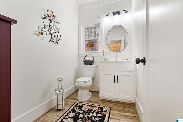 bathroom featuring baseboards, vanity, toilet, and wood finished floors