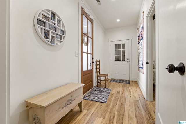 doorway with light wood finished floors, visible vents, baseboards, crown molding, and recessed lighting