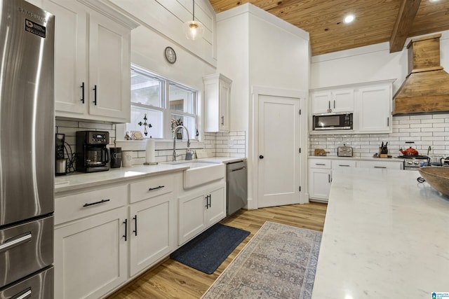 kitchen with custom range hood, appliances with stainless steel finishes, and white cabinets
