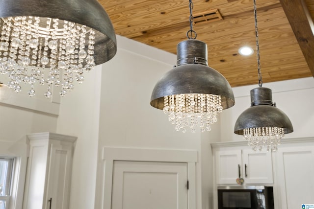 room details with stainless steel microwave, wooden ceiling, white cabinets, and a notable chandelier
