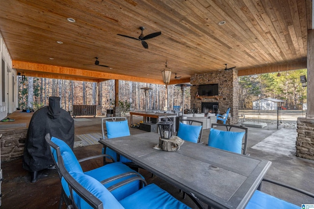 view of patio / terrace with ceiling fan, outdoor dining space, and an outdoor stone fireplace