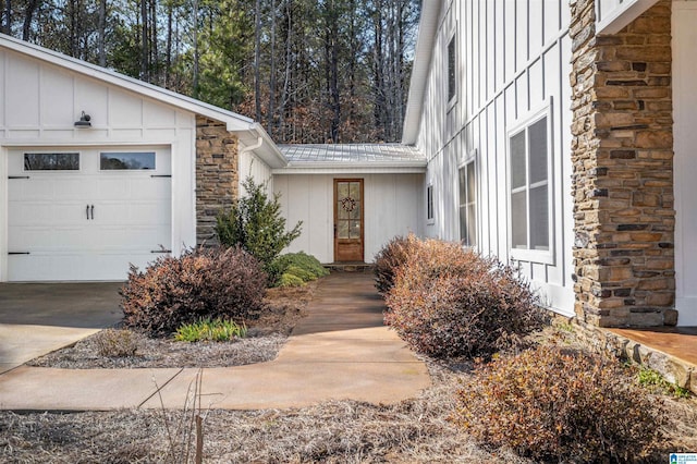 entrance to property with a garage, stone siding, and board and batten siding