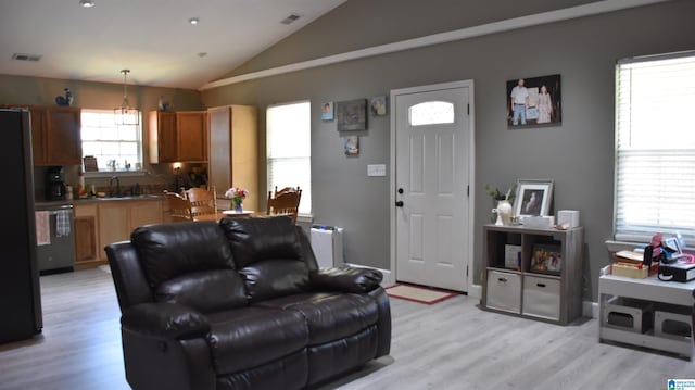 living room with vaulted ceiling, light wood finished floors, and visible vents