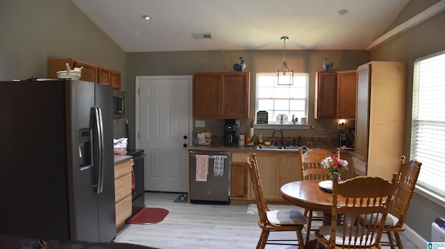 kitchen featuring stainless steel appliances, a sink, visible vents, vaulted ceiling, and hanging light fixtures