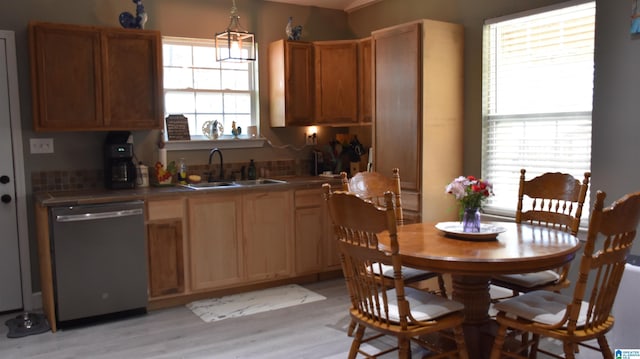 kitchen featuring brown cabinets, light wood finished floors, hanging light fixtures, a sink, and dishwasher