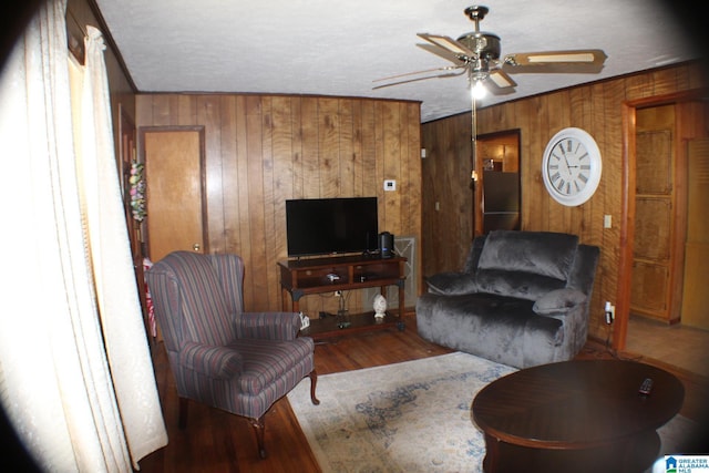 living room featuring wood walls, a ceiling fan, and wood finished floors