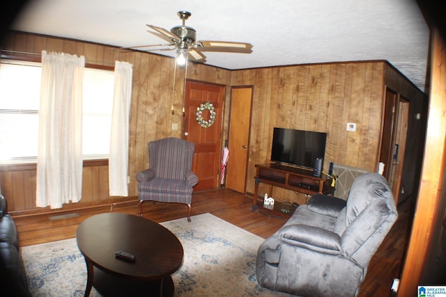 living area with ceiling fan, wood walls, and wood finished floors