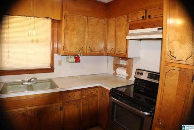 kitchen with brown cabinets, light countertops, electric range, a sink, and under cabinet range hood