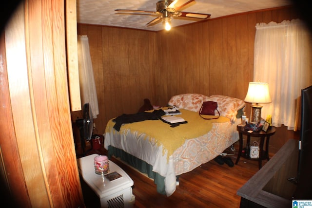 bedroom featuring ceiling fan, wood finished floors, and wooden walls