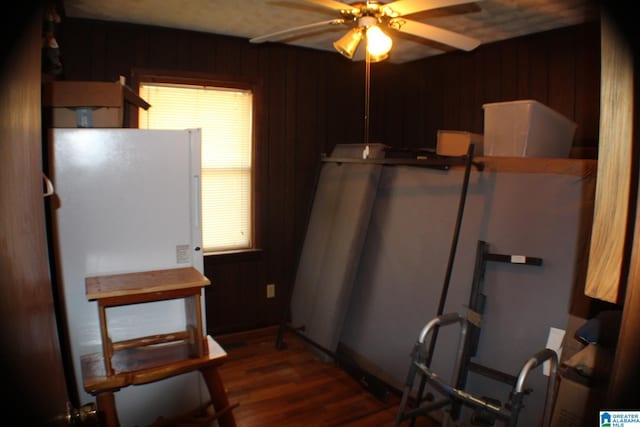 interior space featuring dark wood-style floors, ceiling fan, and wood walls