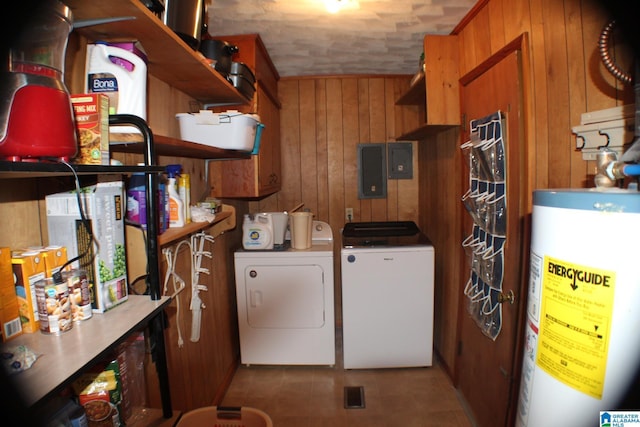 laundry room featuring gas water heater, laundry area, wood walls, washer and dryer, and electric panel