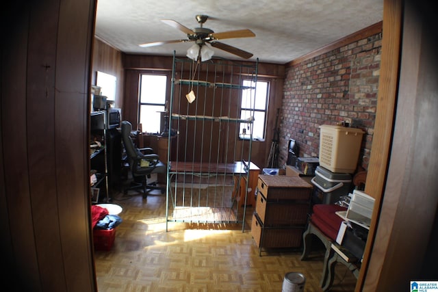 interior space featuring a ceiling fan, a wealth of natural light, wood walls, and a textured ceiling