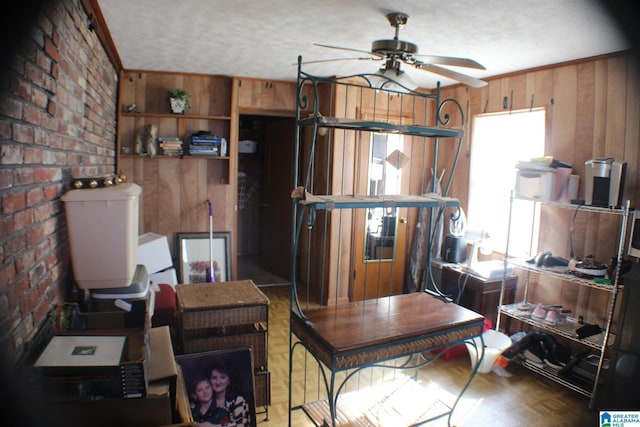 interior space featuring wood walls, ceiling fan, brick wall, and crown molding