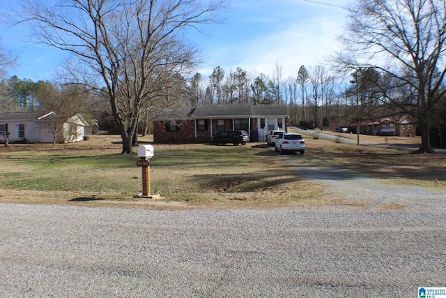 view of front of home with driveway, brick siding, and a front yard