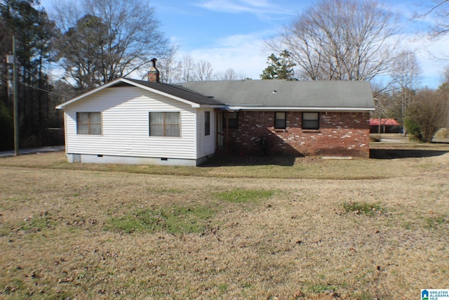 rear view of property with crawl space, brick siding, a chimney, and a yard