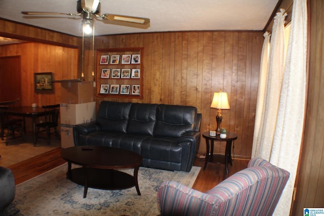 living room with wood walls, light wood-type flooring, and a ceiling fan