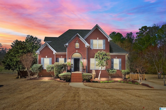 traditional-style home with brick siding and a front lawn