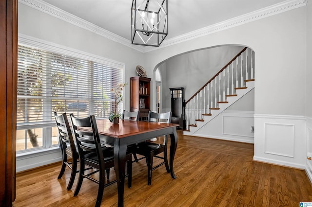 dining space with arched walkways, plenty of natural light, stairway, and wood finished floors