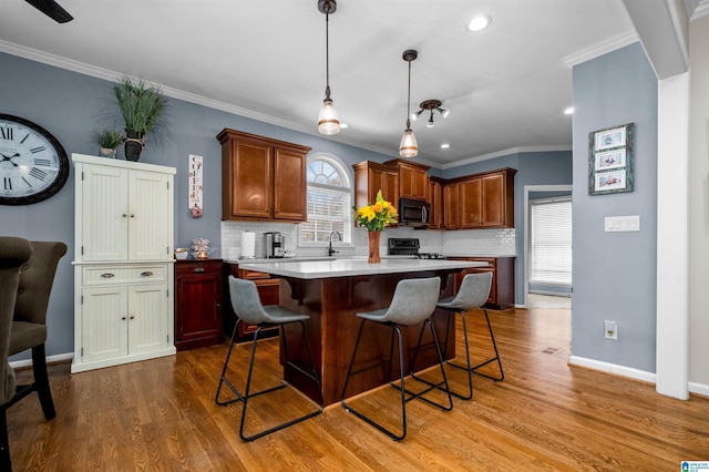 kitchen with light countertops, crown molding, a kitchen breakfast bar, and wood finished floors