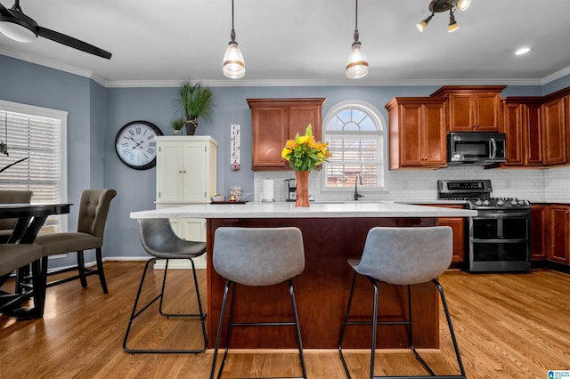 kitchen featuring stainless steel appliances, a center island, light countertops, and wood finished floors