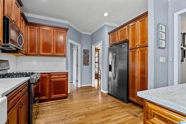 kitchen featuring black microwave, light wood-style floors, fridge with ice dispenser, tasteful backsplash, and stainless steel range with gas stovetop