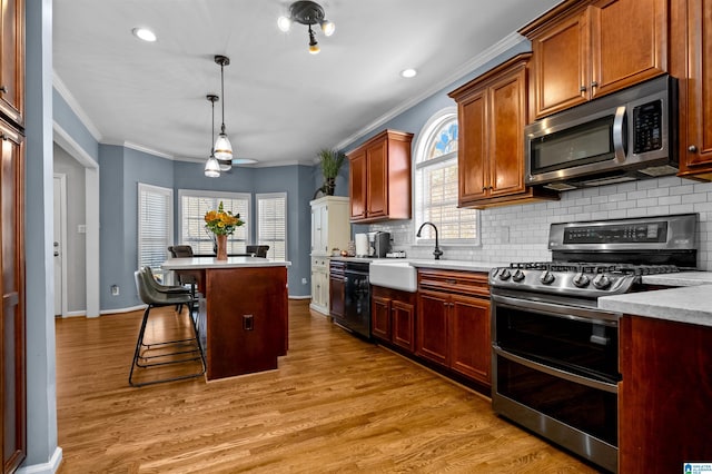 kitchen with stainless steel appliances, a sink, light countertops, and light wood-style floors