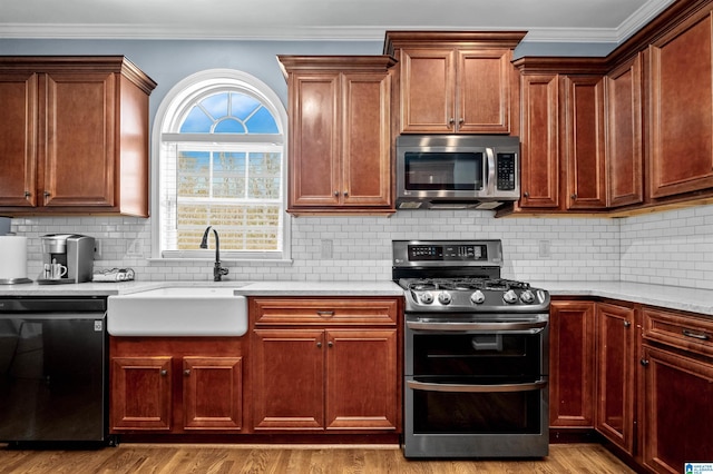 kitchen featuring ornamental molding, appliances with stainless steel finishes, wood finished floors, and a sink