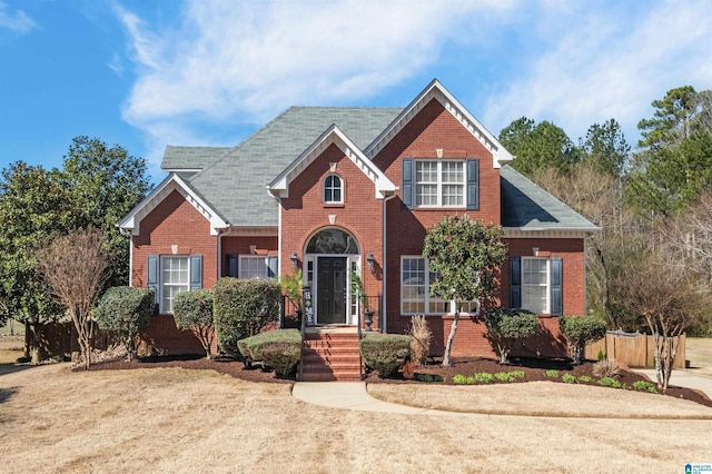 traditional home featuring brick siding and fence