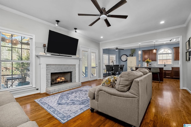 living room featuring recessed lighting, ornamental molding, a brick fireplace, ceiling fan, and wood finished floors