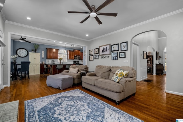 living area featuring arched walkways, crown molding, dark wood finished floors, recessed lighting, and ceiling fan