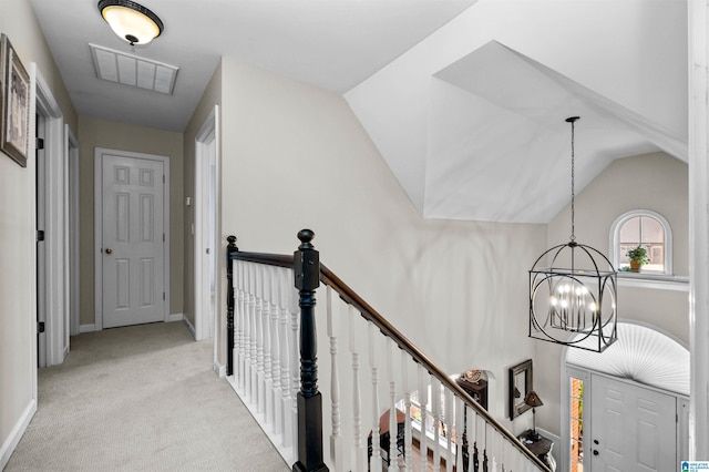 hall featuring a chandelier, light carpet, visible vents, an upstairs landing, and vaulted ceiling