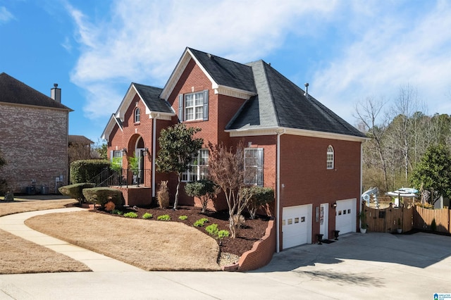 traditional home with brick siding, a shingled roof, fence, a garage, and driveway