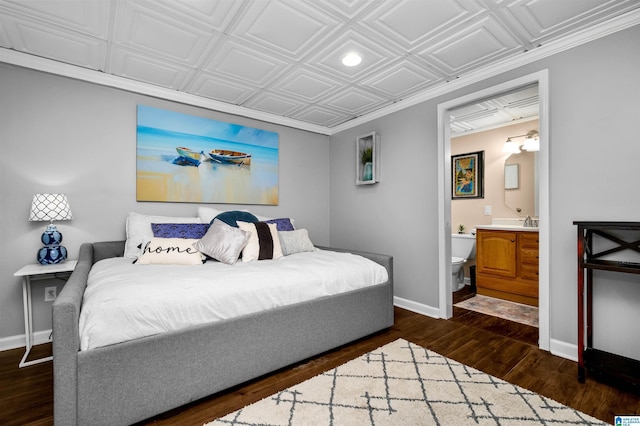 bedroom featuring dark wood-style floors, connected bathroom, an ornate ceiling, and baseboards