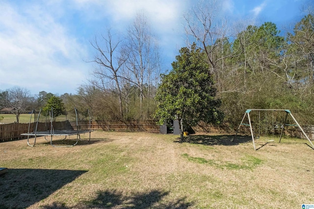 view of yard featuring a trampoline, a playground, and a fenced backyard