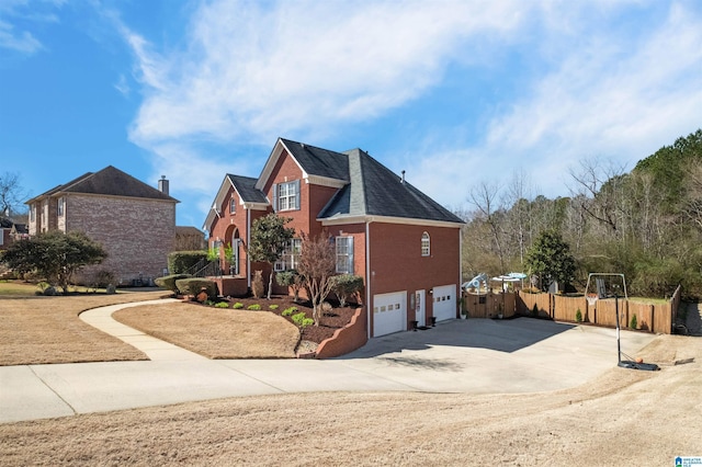 traditional home featuring brick siding, fence, driveway, and an attached garage