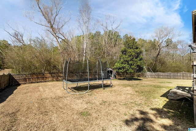 view of yard featuring a trampoline and a fenced backyard