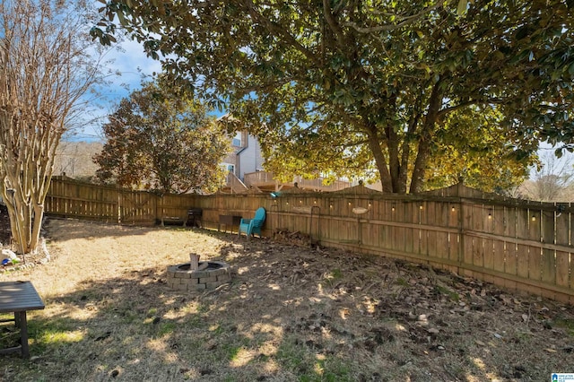 view of yard with a fenced backyard and a fire pit