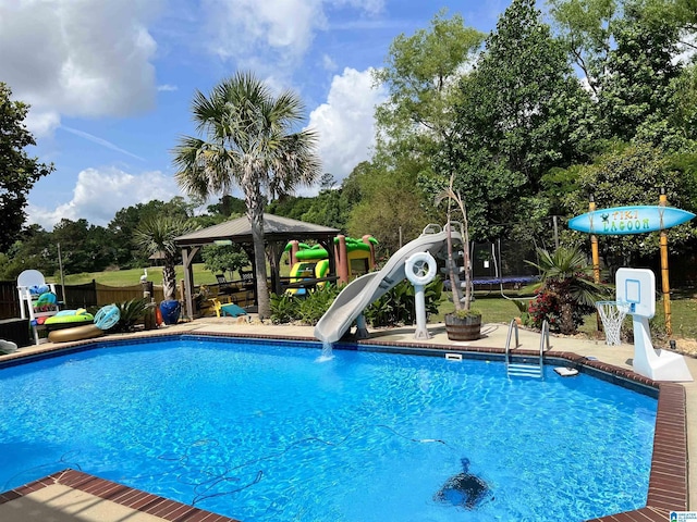 view of swimming pool featuring a fenced in pool, a trampoline, a water slide, and a gazebo