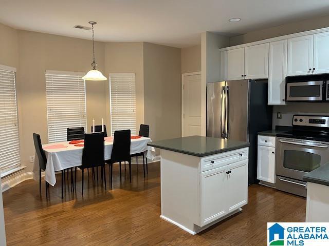 kitchen featuring appliances with stainless steel finishes, dark countertops, white cabinetry, and pendant lighting