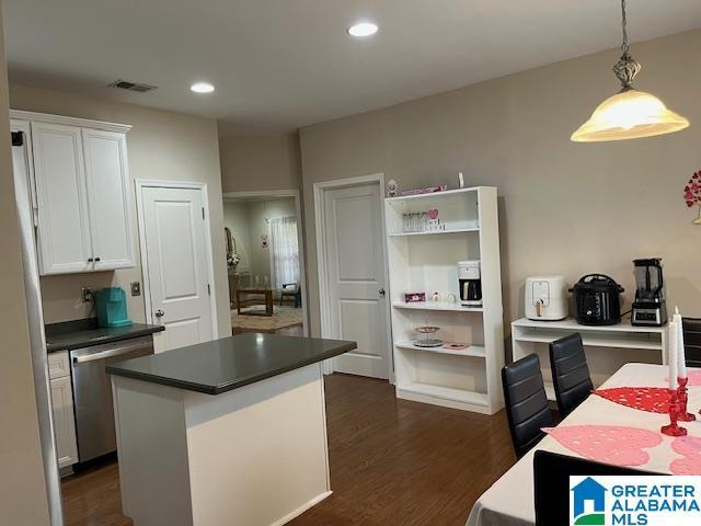 kitchen featuring visible vents, white cabinetry, stainless steel dishwasher, a center island, and dark countertops