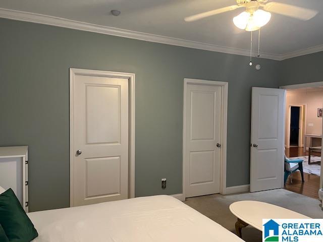 carpeted bedroom featuring baseboards, a ceiling fan, and crown molding