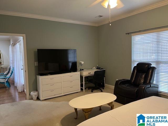 bedroom featuring ornamental molding, light carpet, baseboards, and a ceiling fan