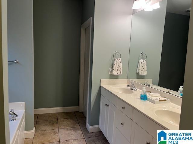 full bath featuring a bath, baseboards, a sink, and tile patterned floors