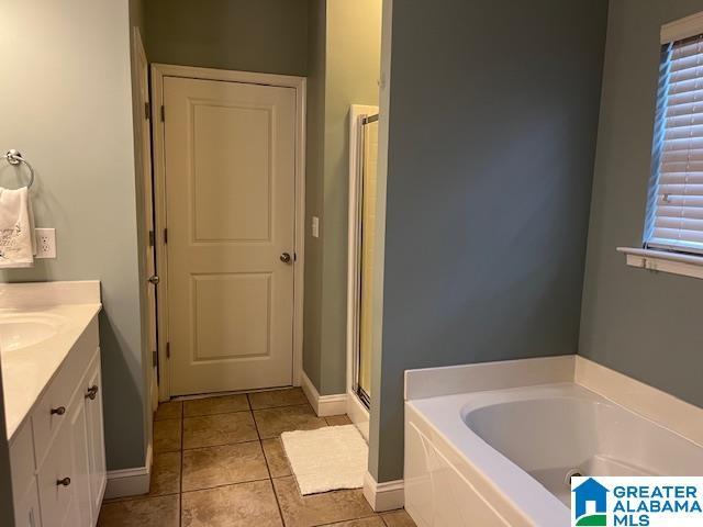 bathroom featuring tile patterned flooring, a shower stall, a bath, and vanity