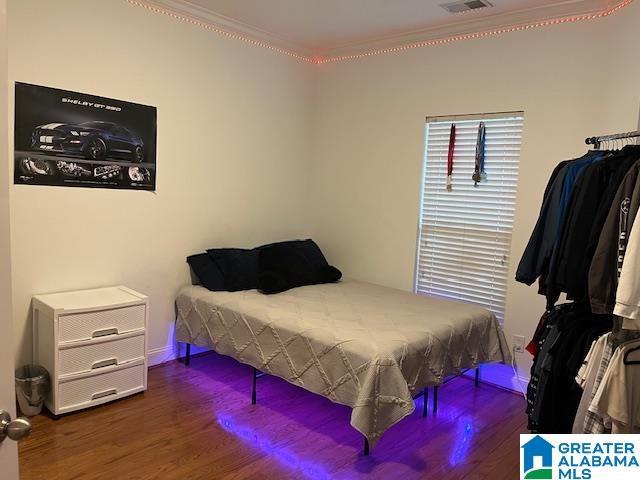 bedroom with visible vents, dark wood-style flooring, and crown molding